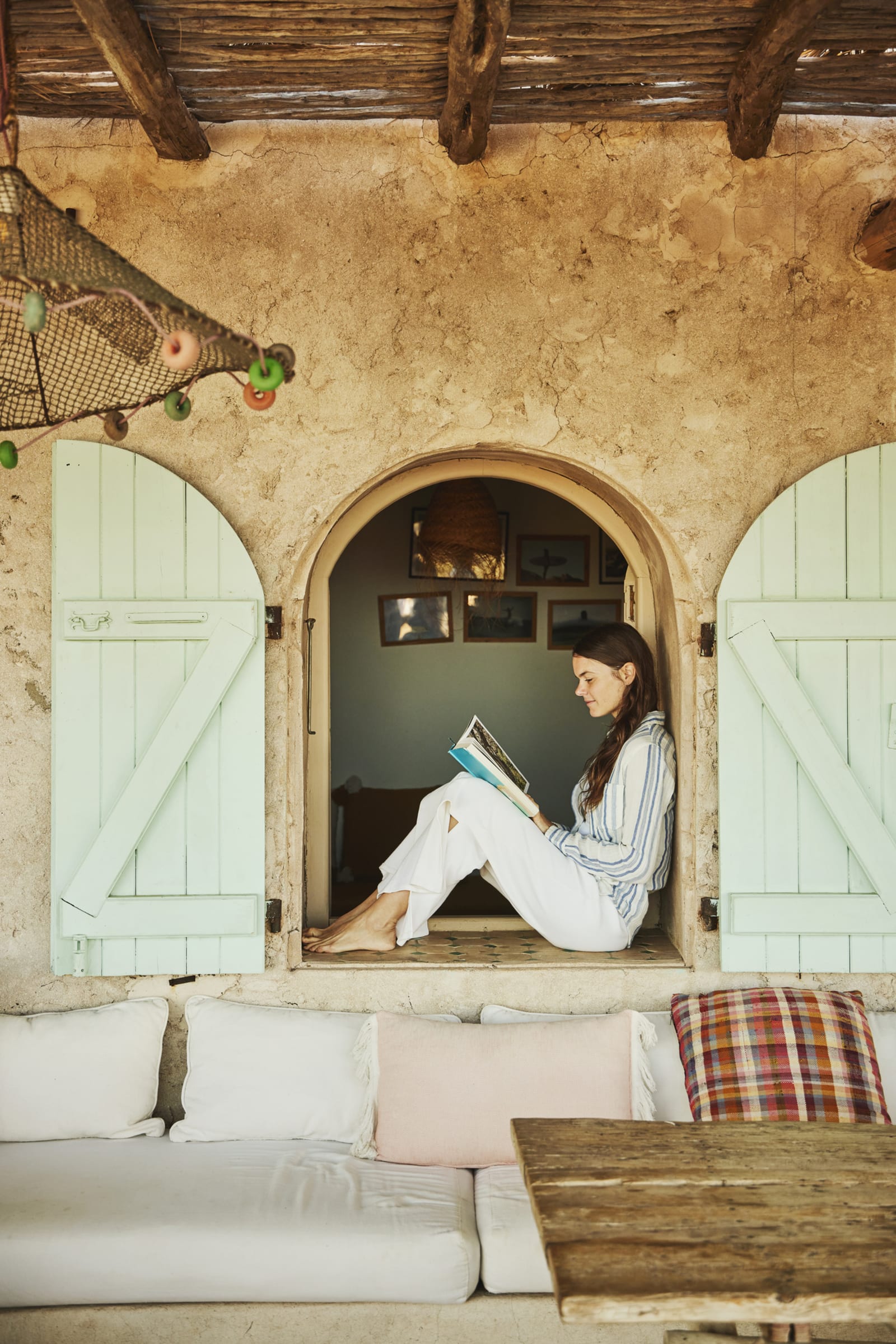 Woman sitting in window while reading book during holiday