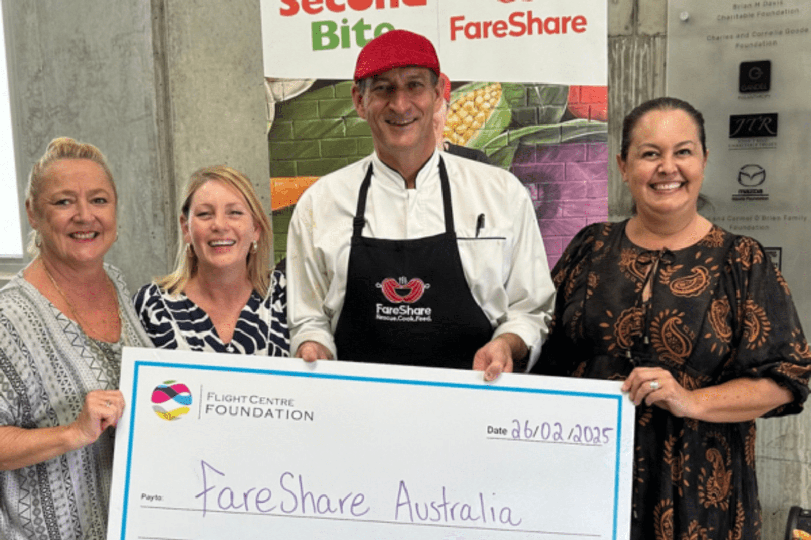 People smiling, holding a large check