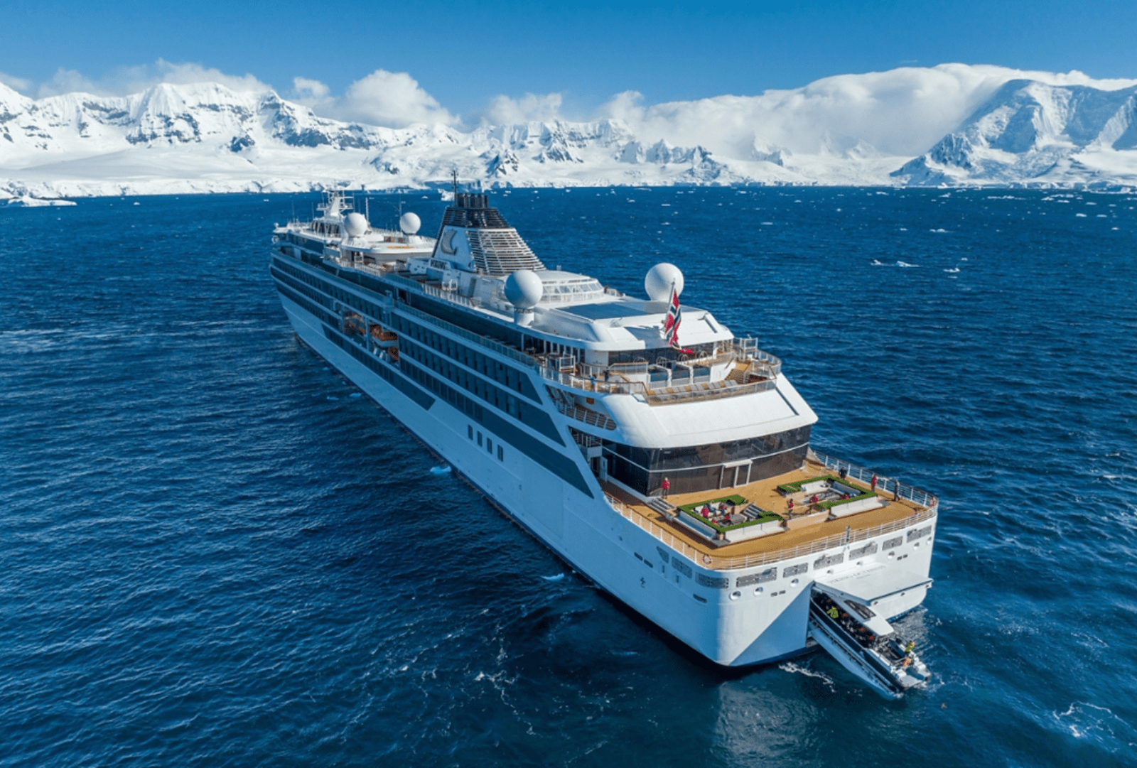 Viking Octantis expedition ship sailing through icy waters beneath snow capped Antarctic mountains