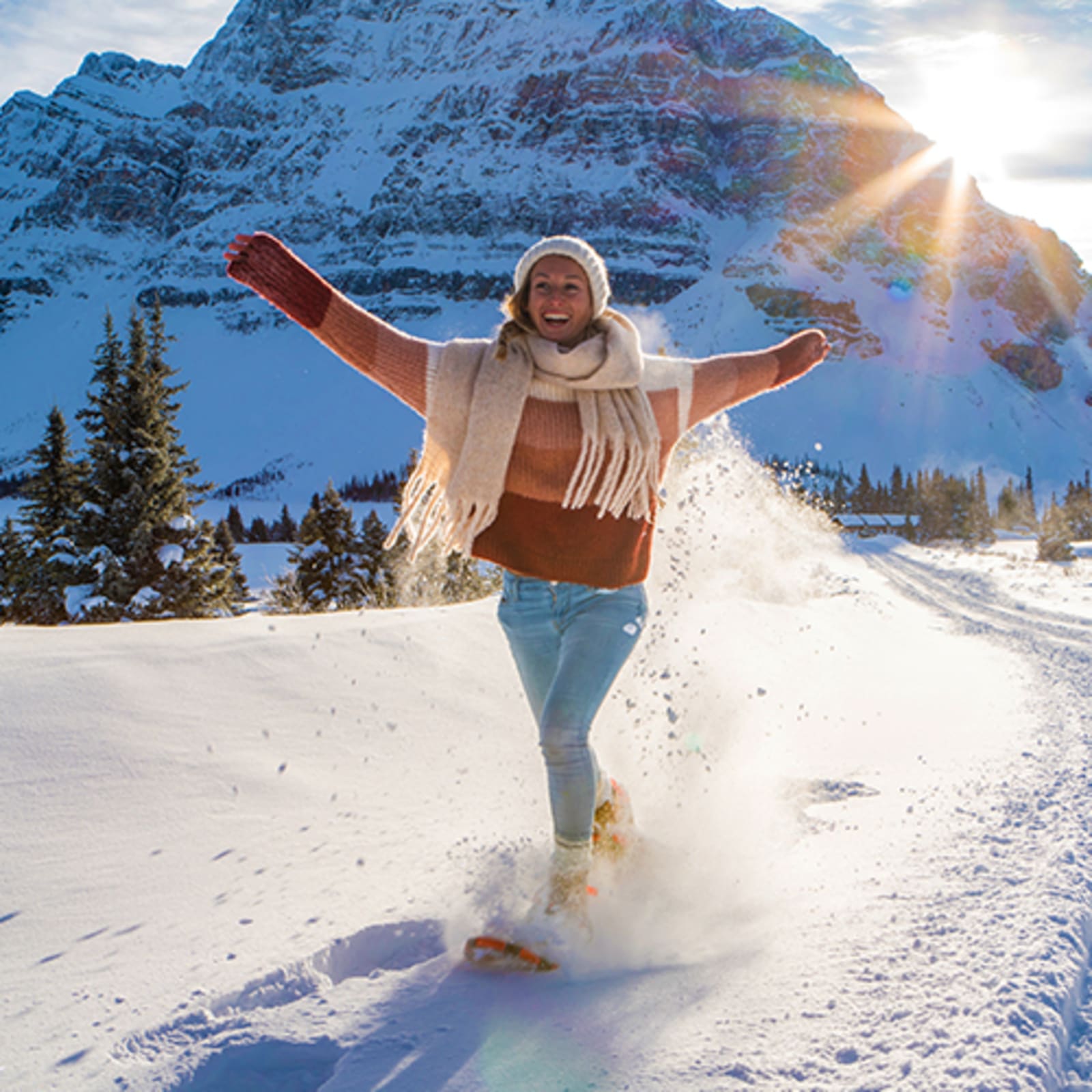 Woman wearing snow shoes walking on a bright, sunny day