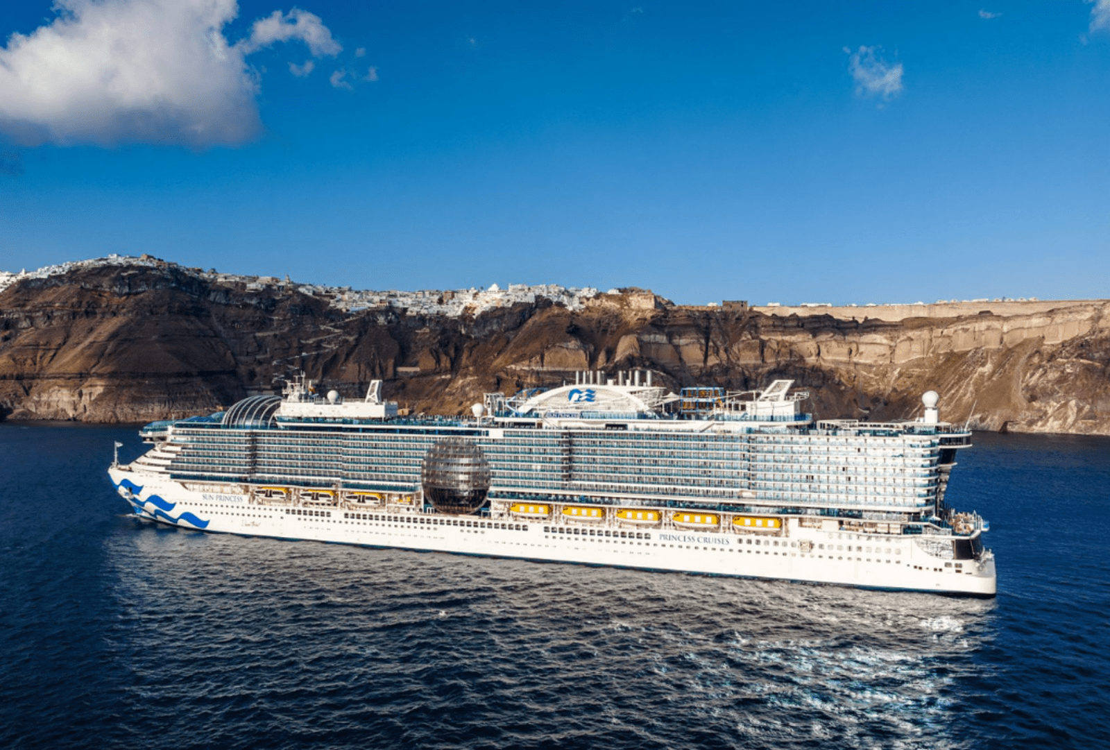 Star Princess sailing past the dramatic clifftop villages of Santorini under a clear blue sky