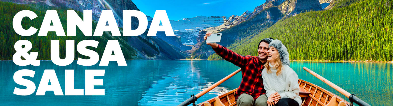 A couple enjoying a canoe ride on a turquoise lake surrounded by forested mountains in Canada, smiling and taking a selfie under clear blue skies and scenic outdoor adventures in North America.