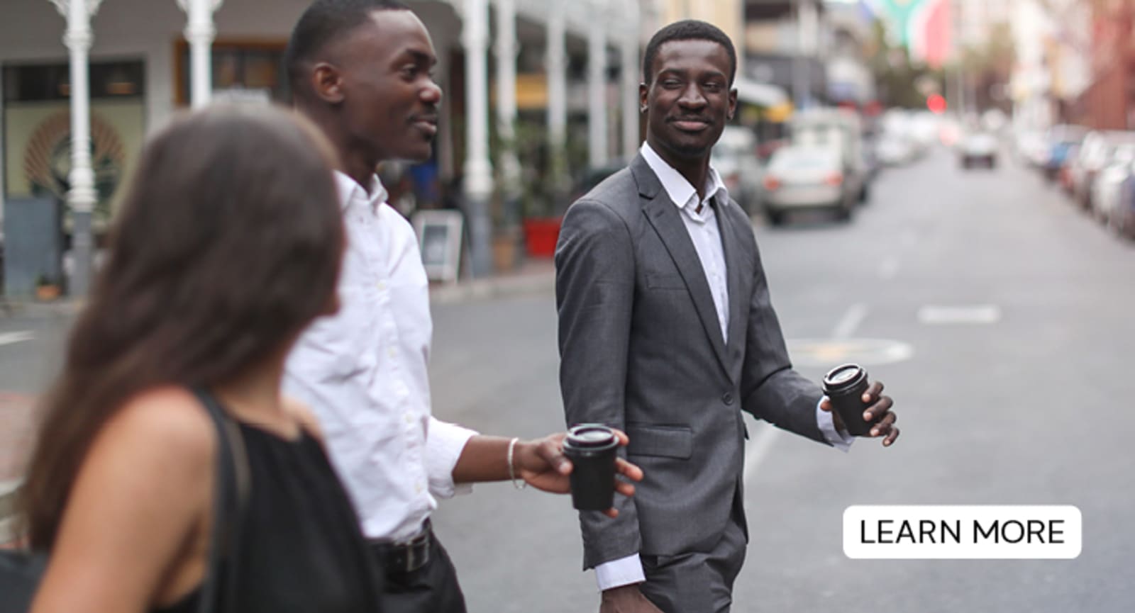 People in business suits crossing the street, drinking coffee