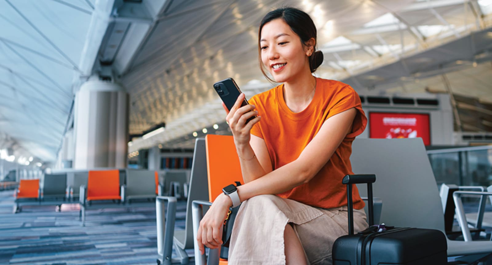 Woman wearing orange on her phone in an airport