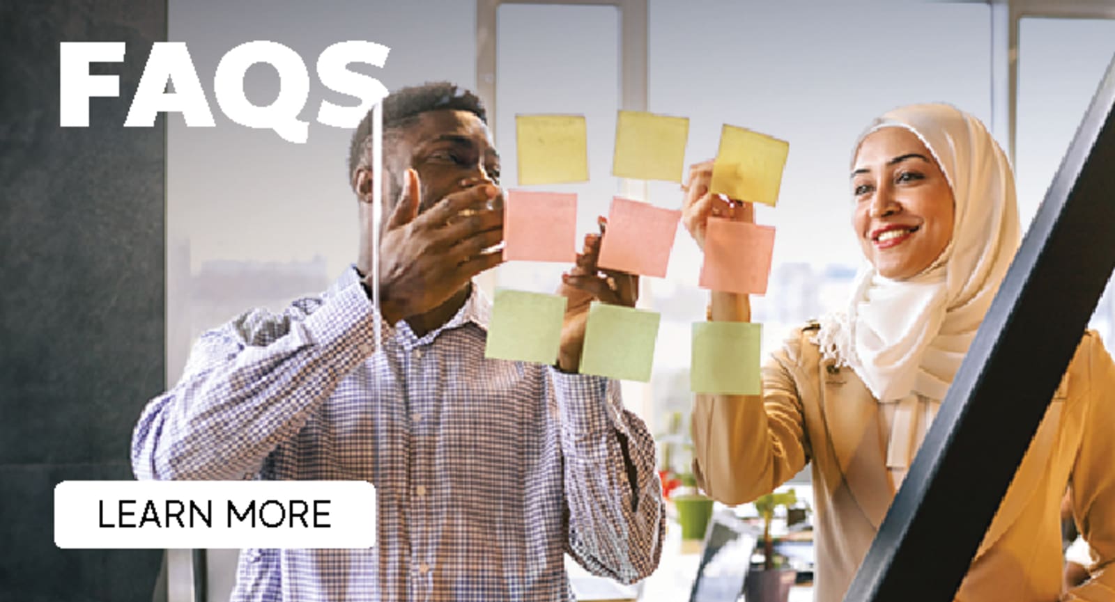 Two business people sharing colourful sticky notes on the glass window of a meeting room