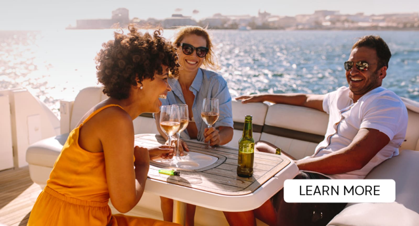 Three people laughing and enjoying wine on a luxury yacht on a sunny day