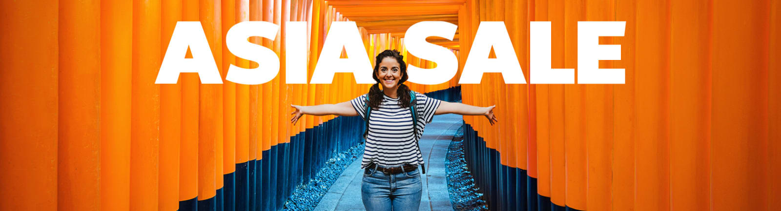 A smiling traveler stands with arms outstretched along a pathway of vibrant orange torii gates at a Japanese shrine, wearing a striped shirt and backpack. Bold white text at the top reads “ASIA SALE.”