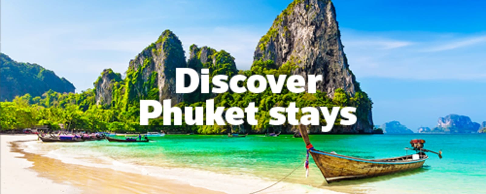 Taditional longtail boat on a white sand beach with turquoise waters and limestone cliffs