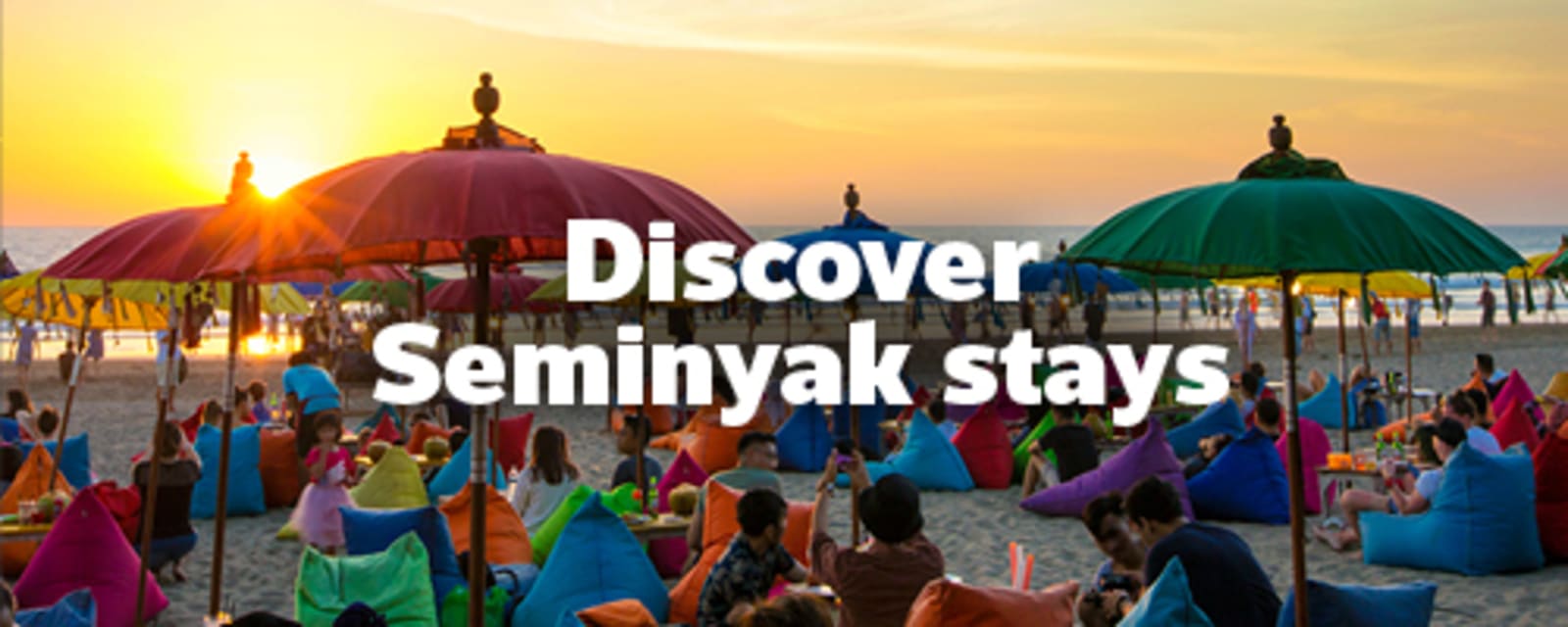 People sitting on colourful beanbags on the beach at sunset