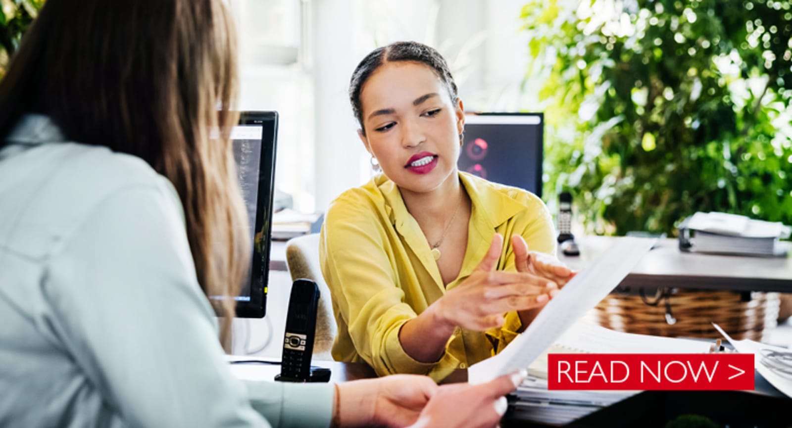 Two businesswomen meeting over paperwork