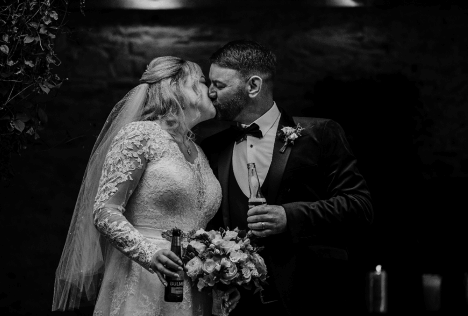 Bride (Geraldine) and Groom (Tom) kiss holding drinks at their wedding in Dublin 