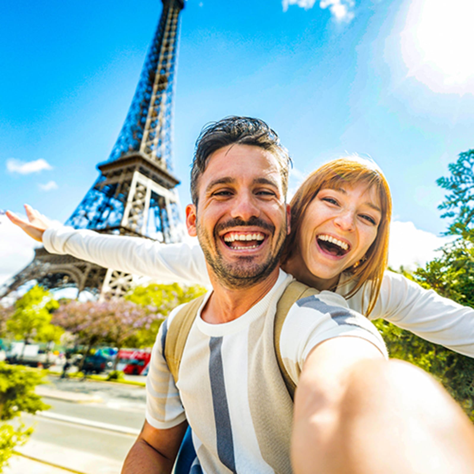Couple smiling, taking a selfie in front of the Eifel Tower