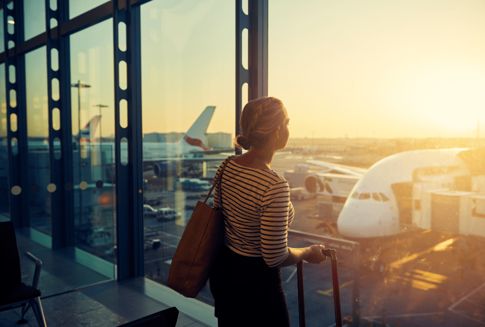 A young woman looking through the window of an airport departure lounge