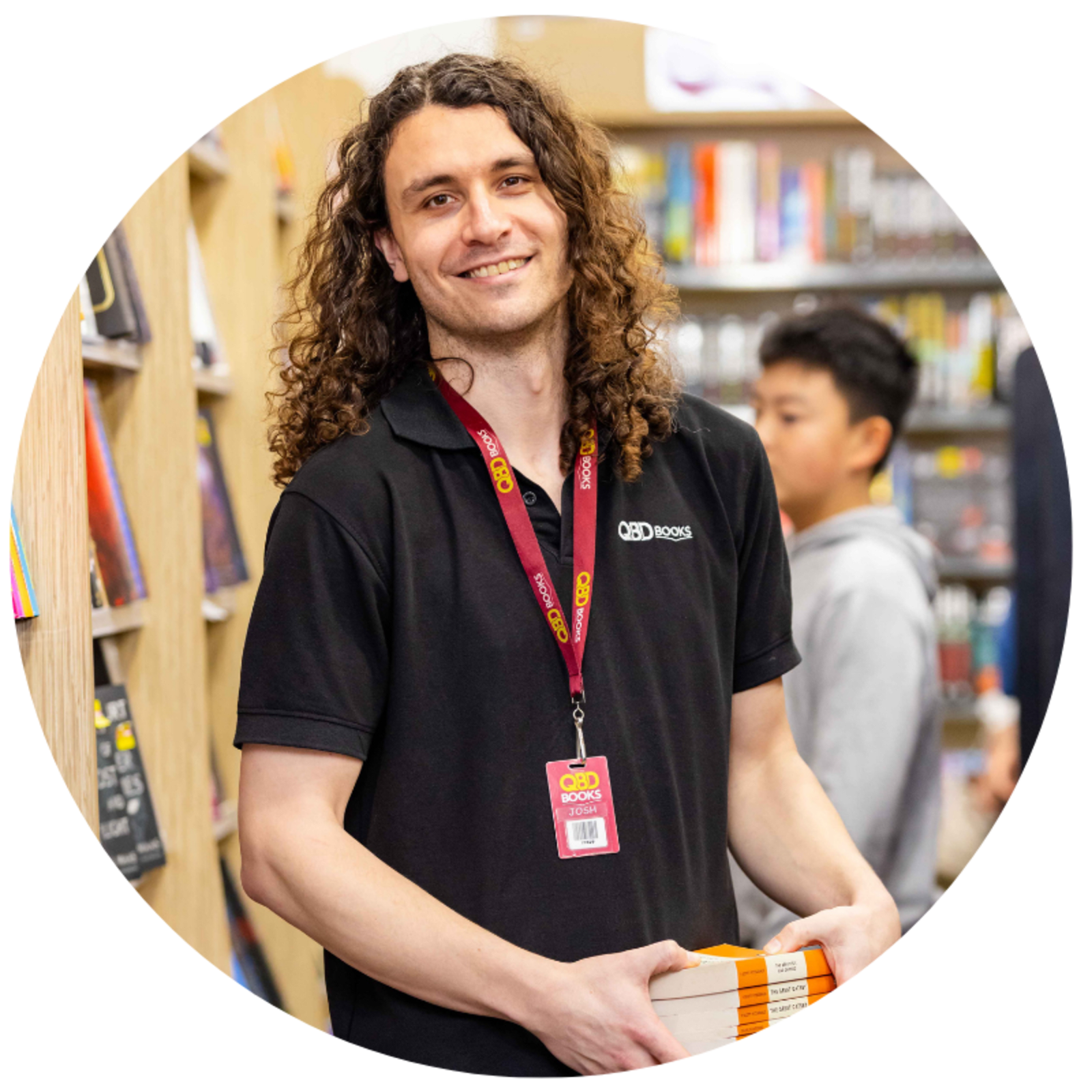 An employee of QBD holds a stack of books