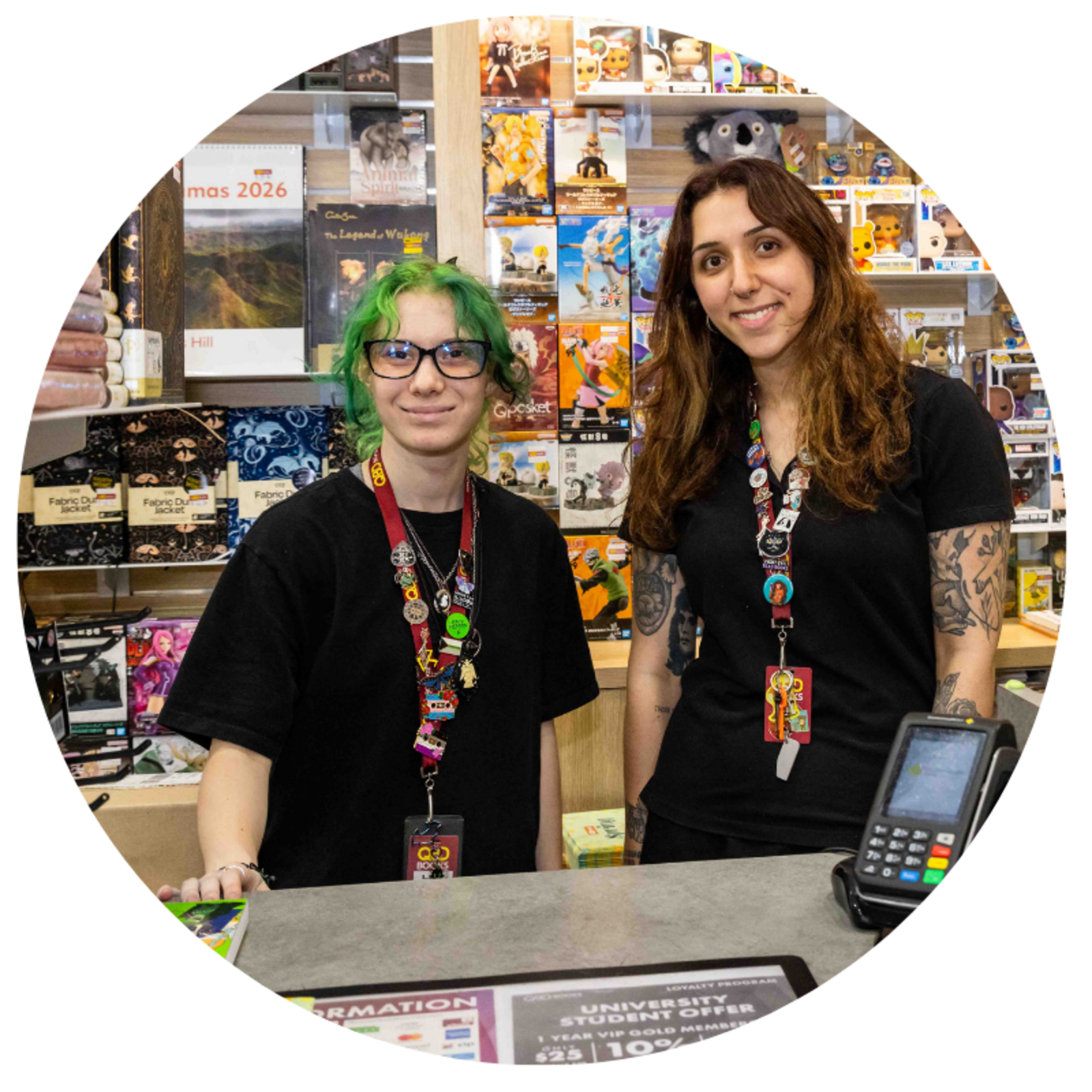Two employees of QBD Books smile behind the counter