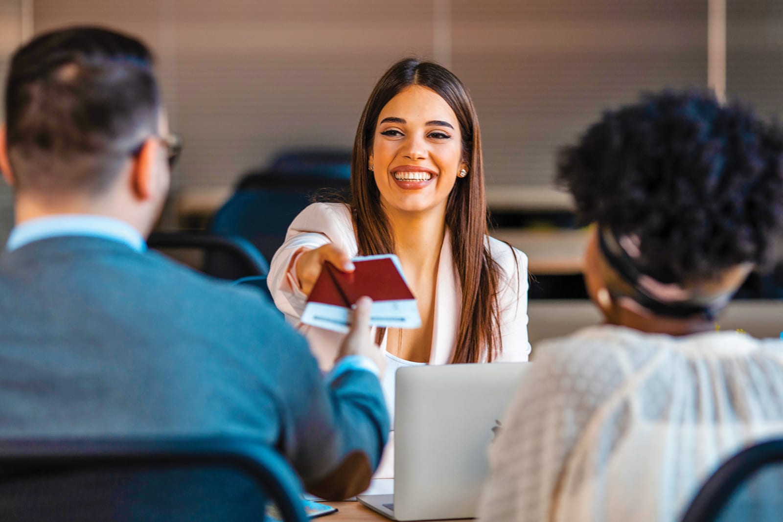 Woman in business suit handing passports and flight tickets to a couple