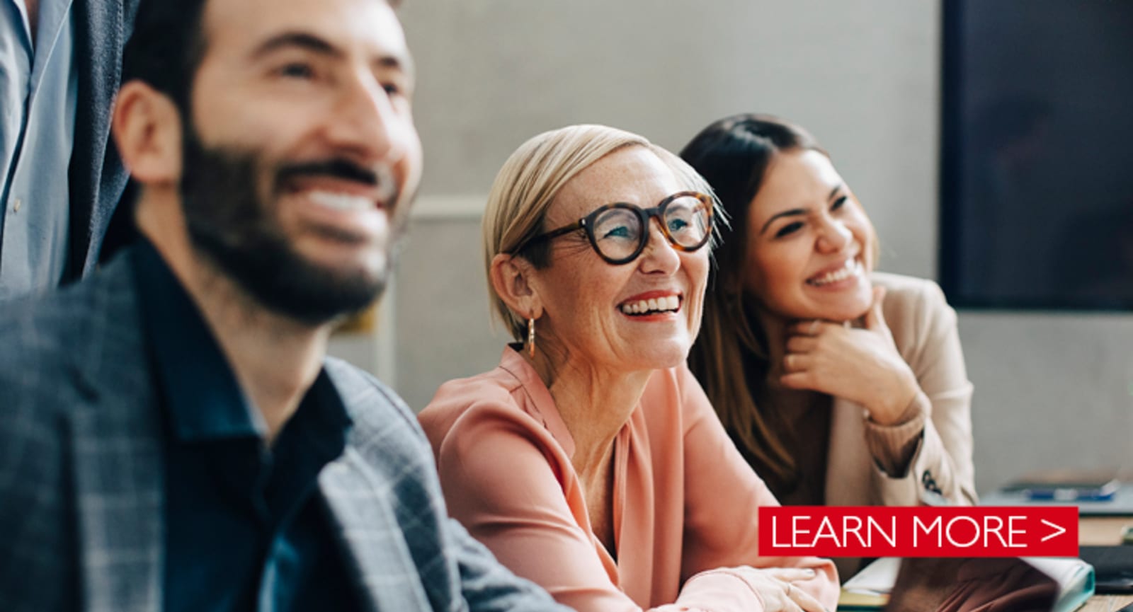 Closeup of 3 smiling people, focusing on an elderly woman wearing glasses
