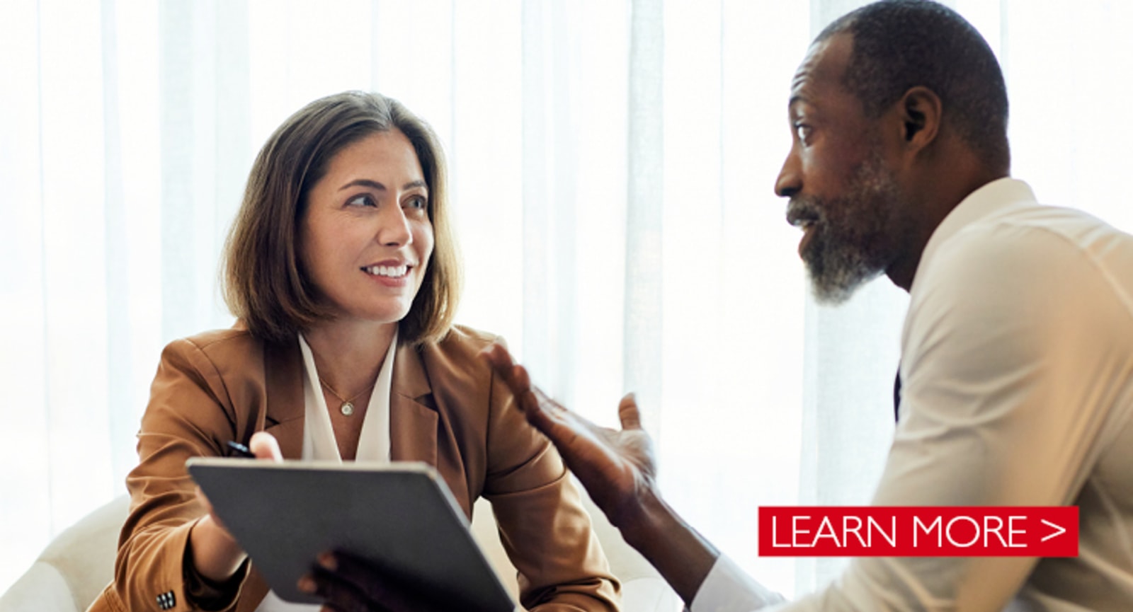 White businesswoman and black businessman talking while gesturing at a tablet