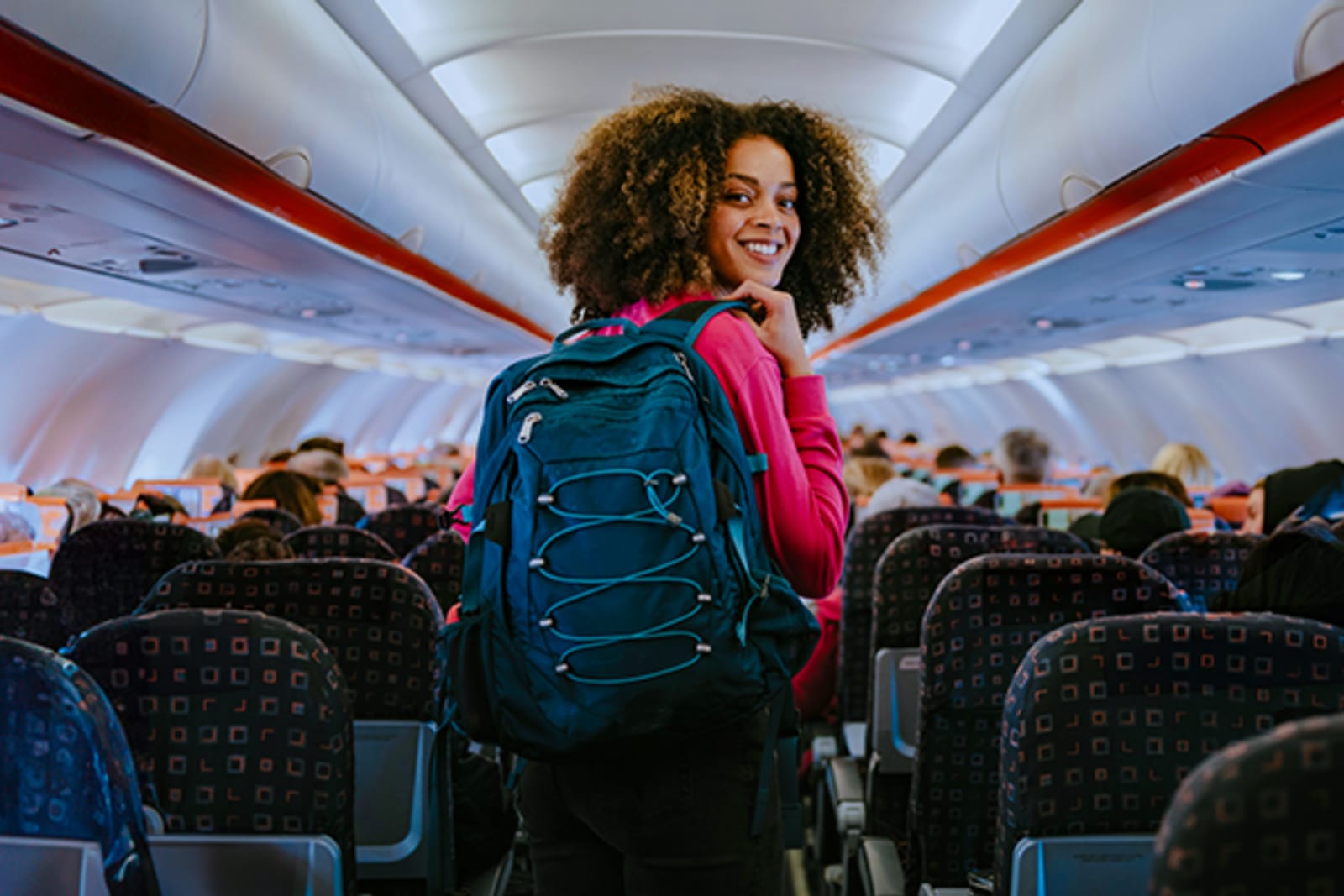 Woman with backpack standing in the aisle of a plane