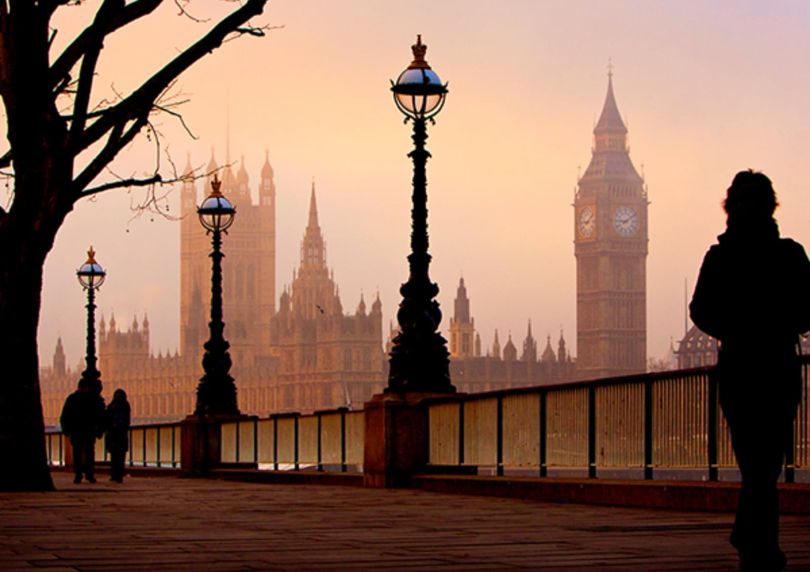 People in shadow walking along a river with Elizabeth Tower / Big Ben in the background