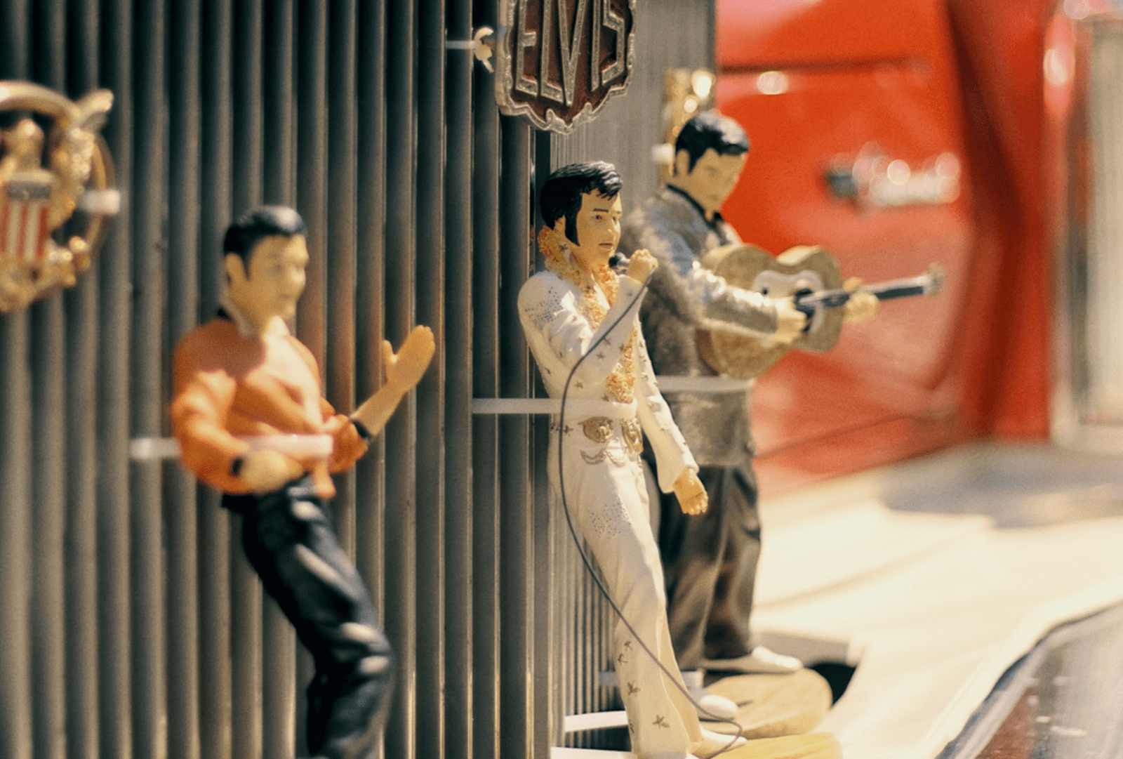 Vintage Elvis figurines zip tied to the grill of a classic red car