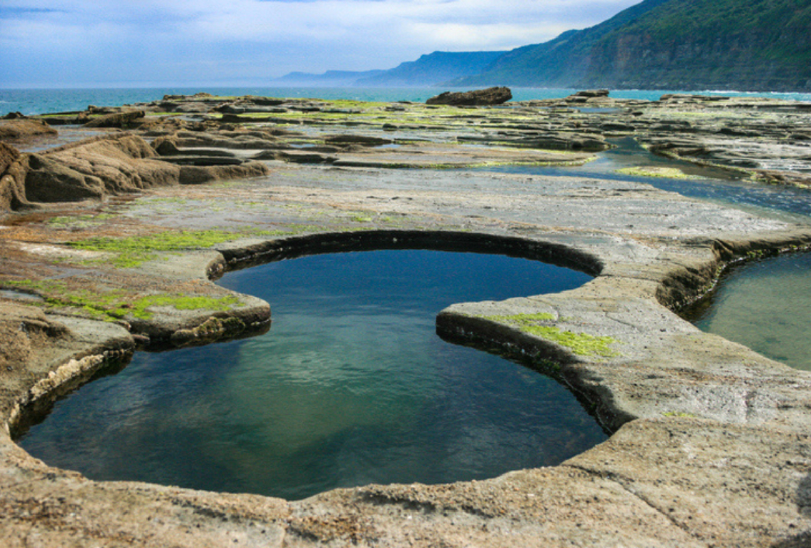 A rock pool cut naturally into a figure-8 with ocean views beyond at Royal National Park, NSW