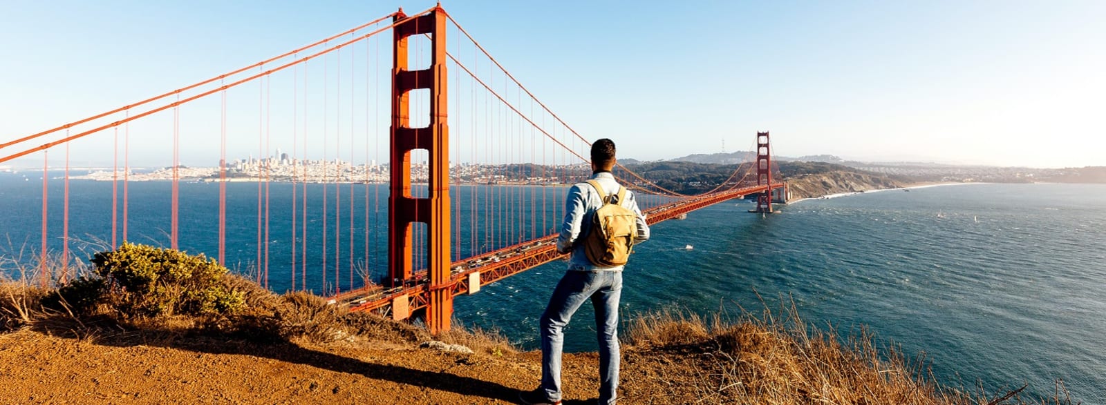 Backpacker standing on a hill looking out at the Golden Gate Bridge