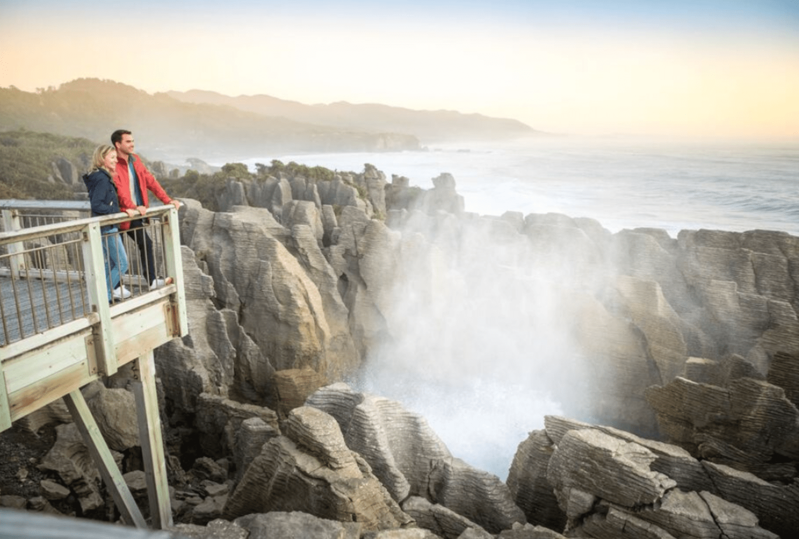 A couple watch sea spray from a blowhole, Pancake Rocks, Punakaiki, NZ