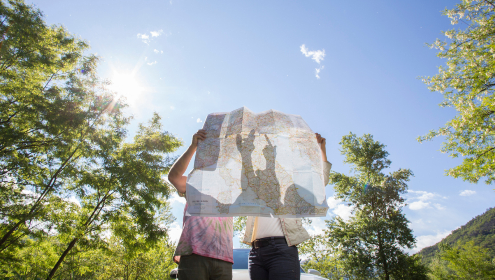 The shadow of two people showing through a paper map of Italy as they analyse it and point