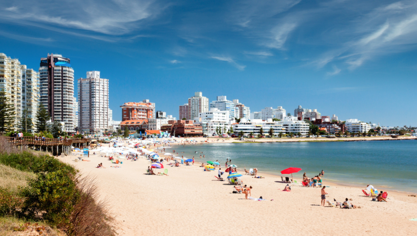 Beach with people and beach umbrellas with buildings in the background