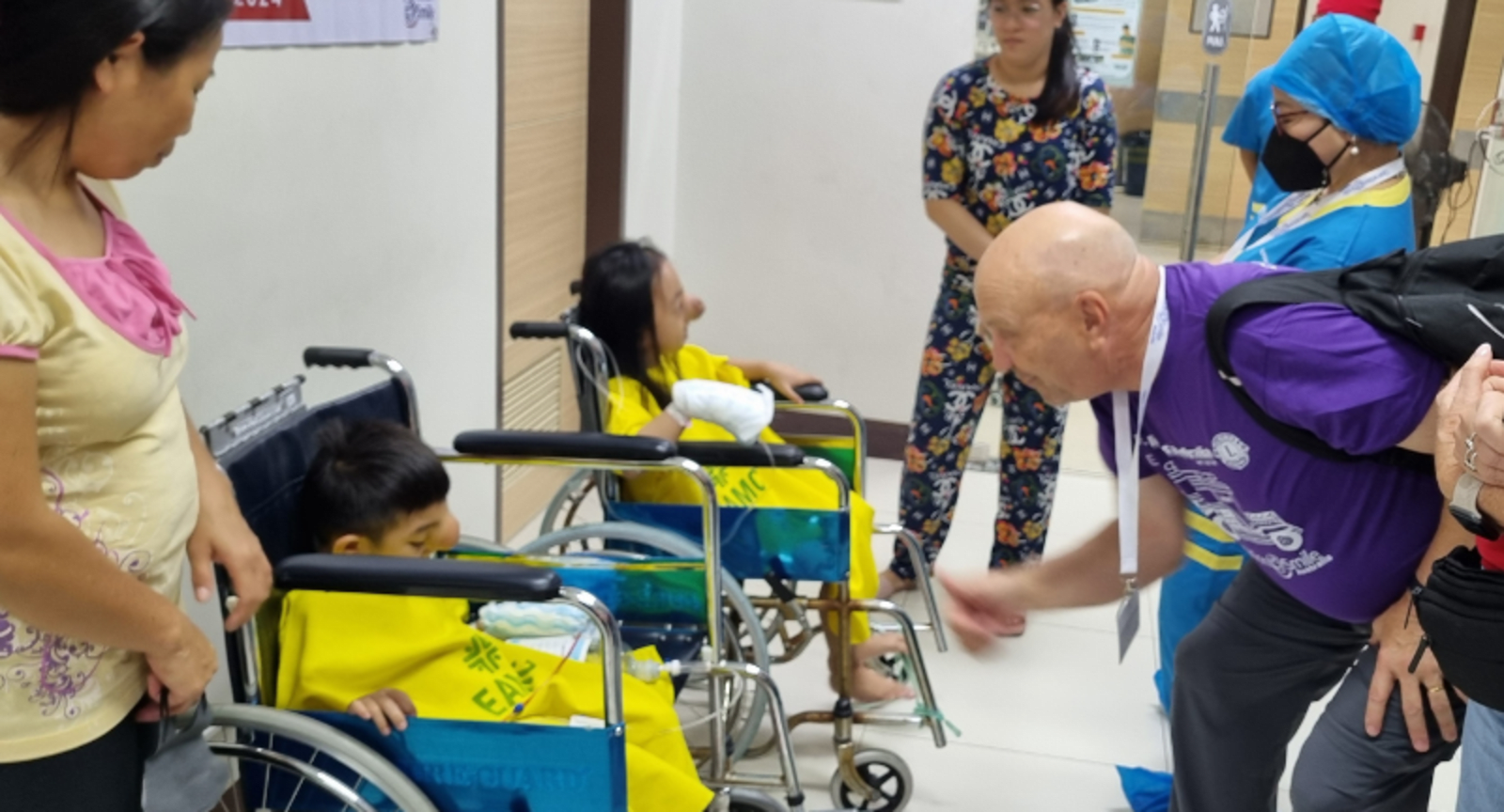Man entertaining children in wheelchairs at a hospital