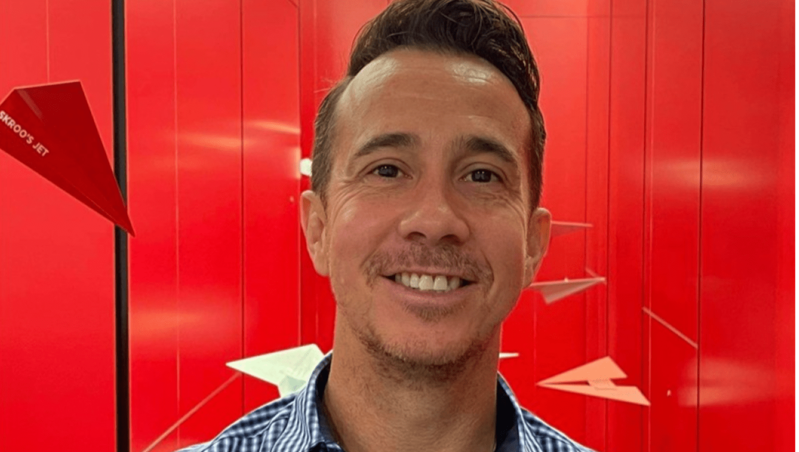 Jonathan Tas smiling on red background