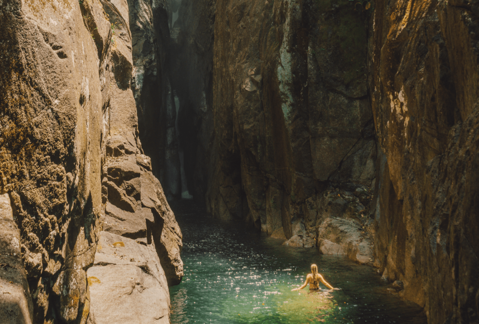 Silky waterfall cascading into a serene rock pool surrounded by lush tropical rainforest at Babinda Boulders near Cairns in Queensland
