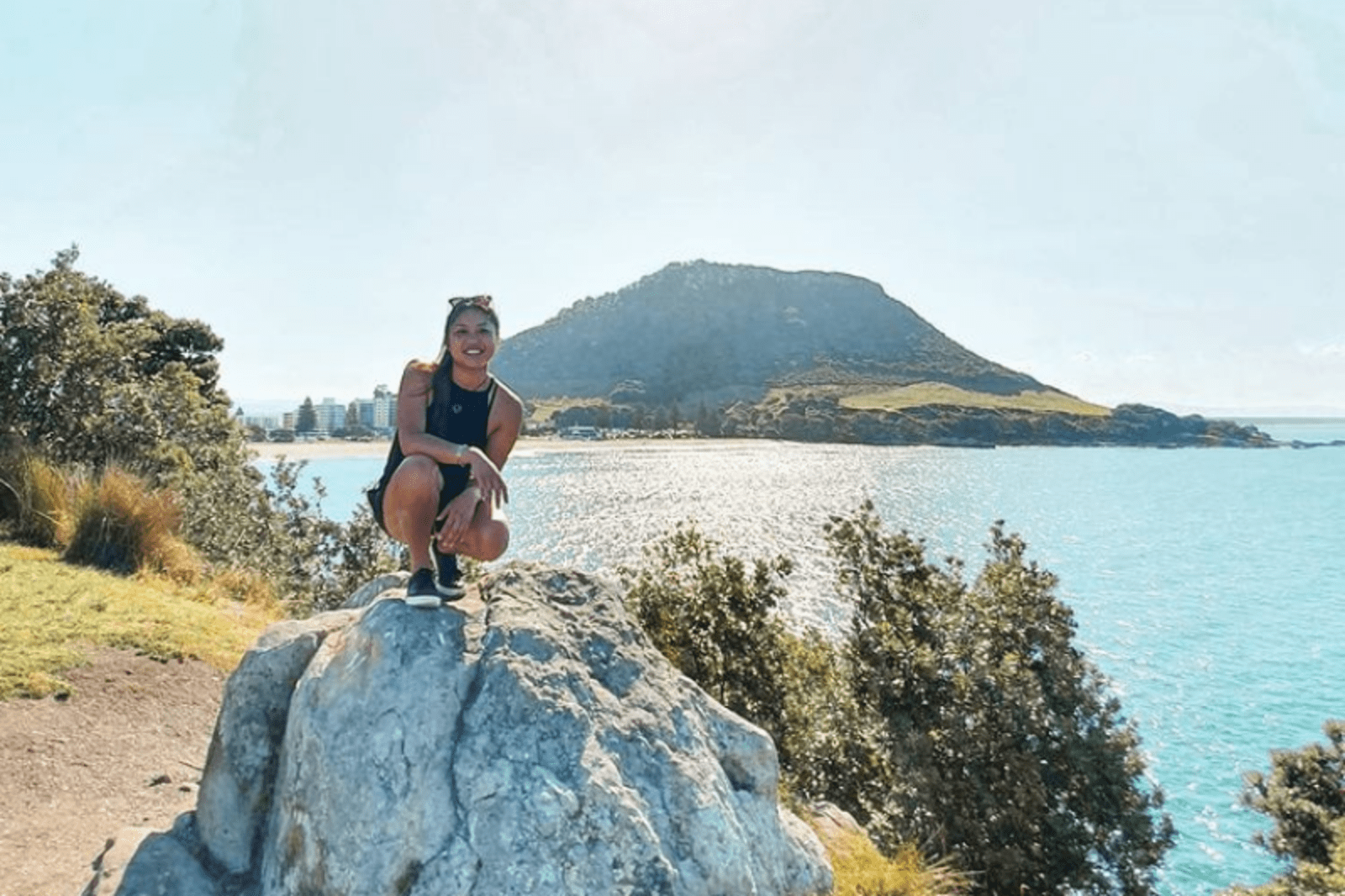 Lady crouching on rock with islands and water behind