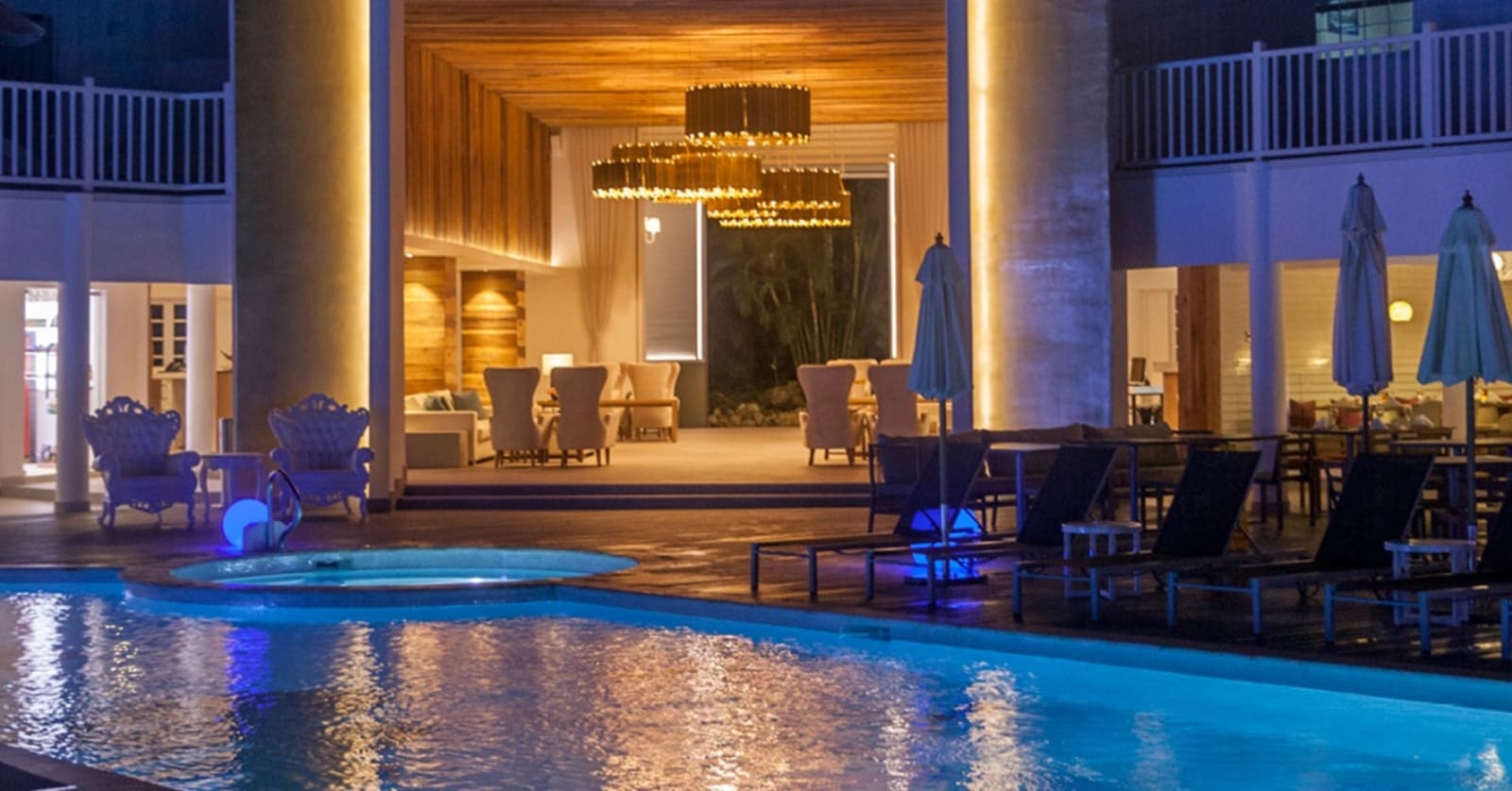 Azul beach resort in Negril - open air lounge lit by warm lighting next to a blue-lit pool at nighttime