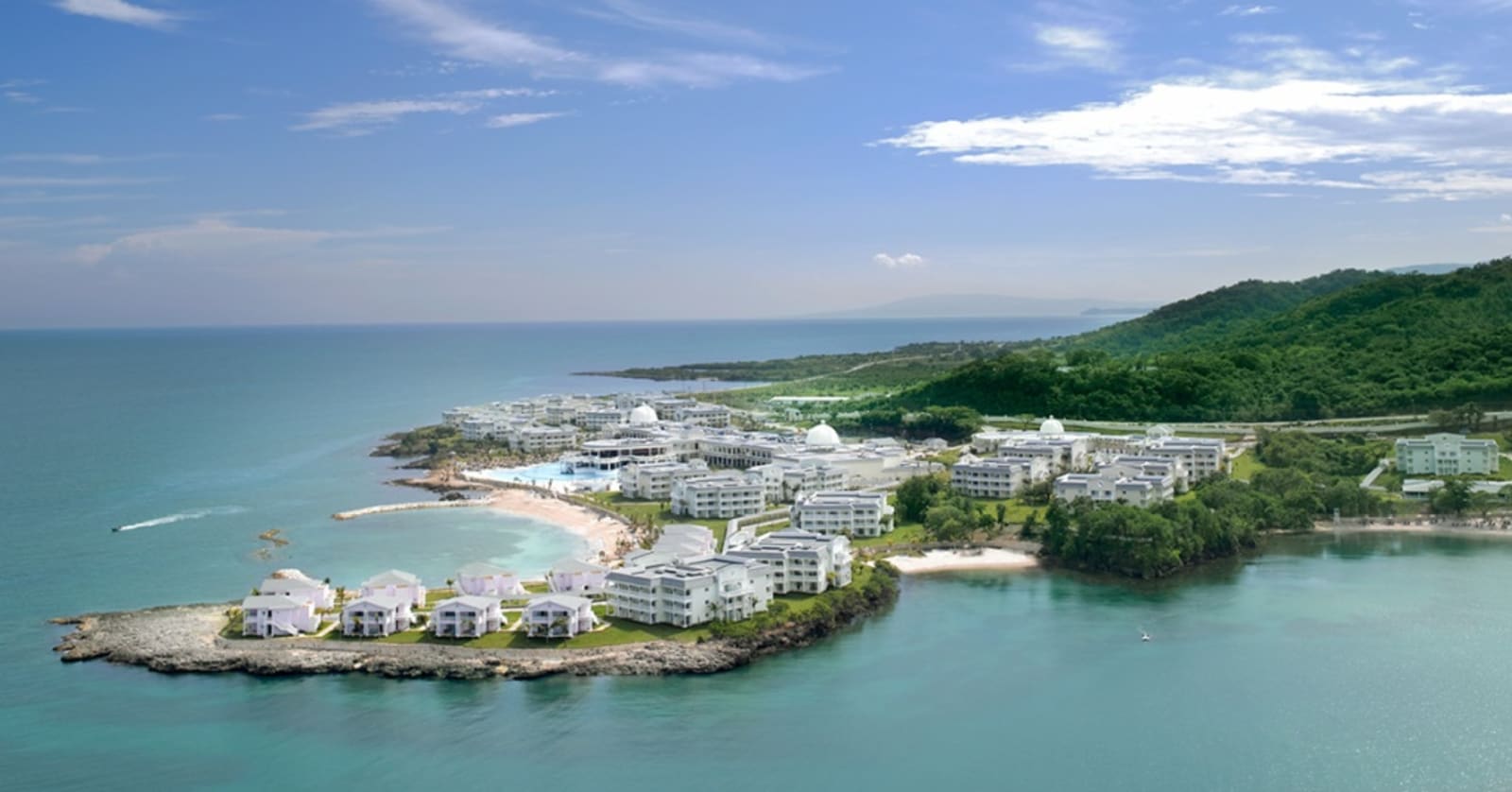 Several white resort buildings on a C-shaped cove