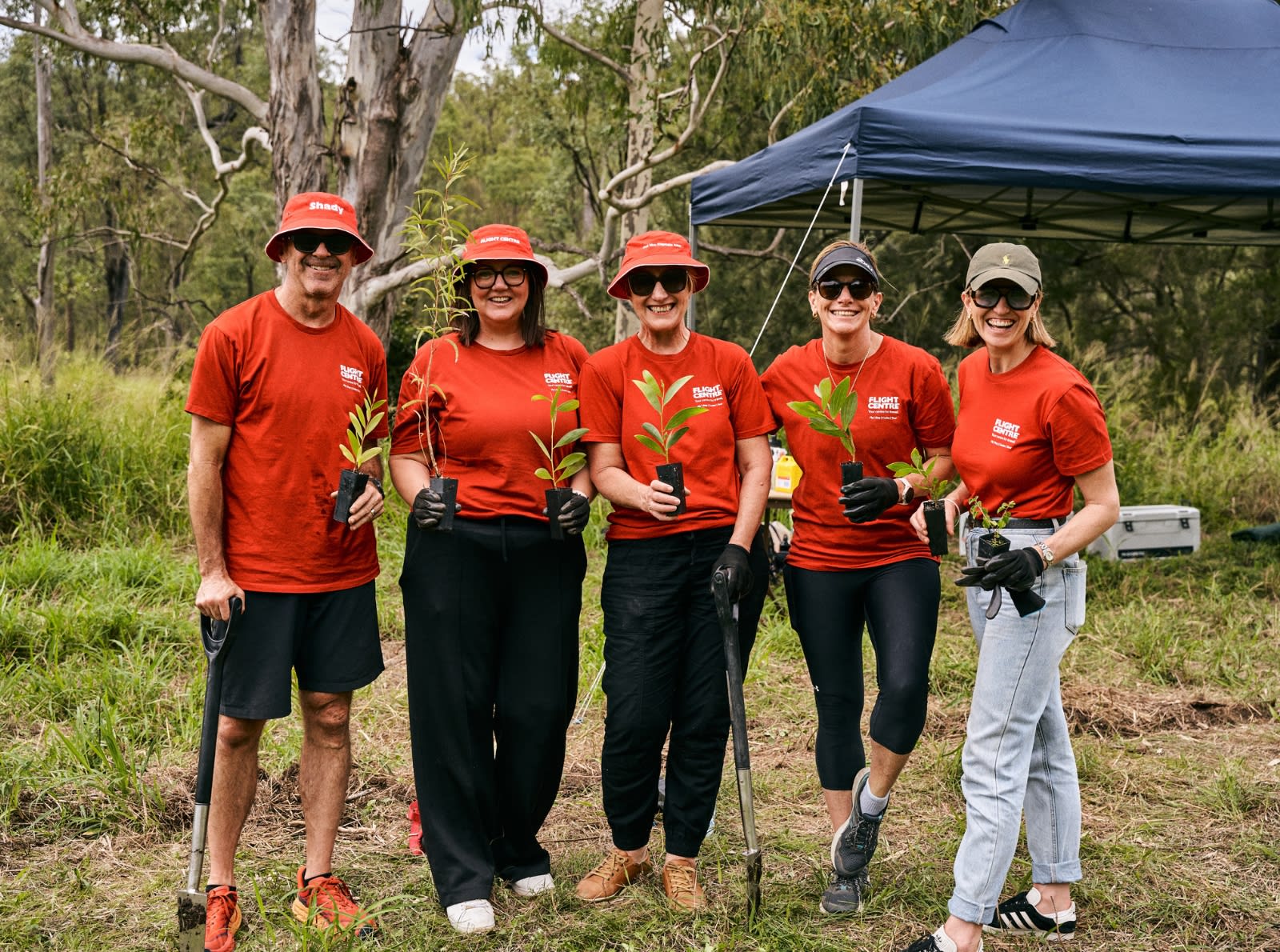 people holding trees and wearing red shirts
