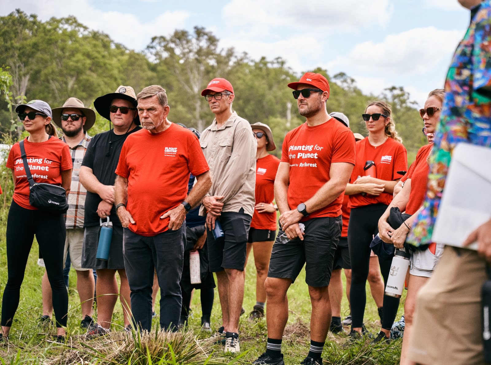people in red shirts standing and listening