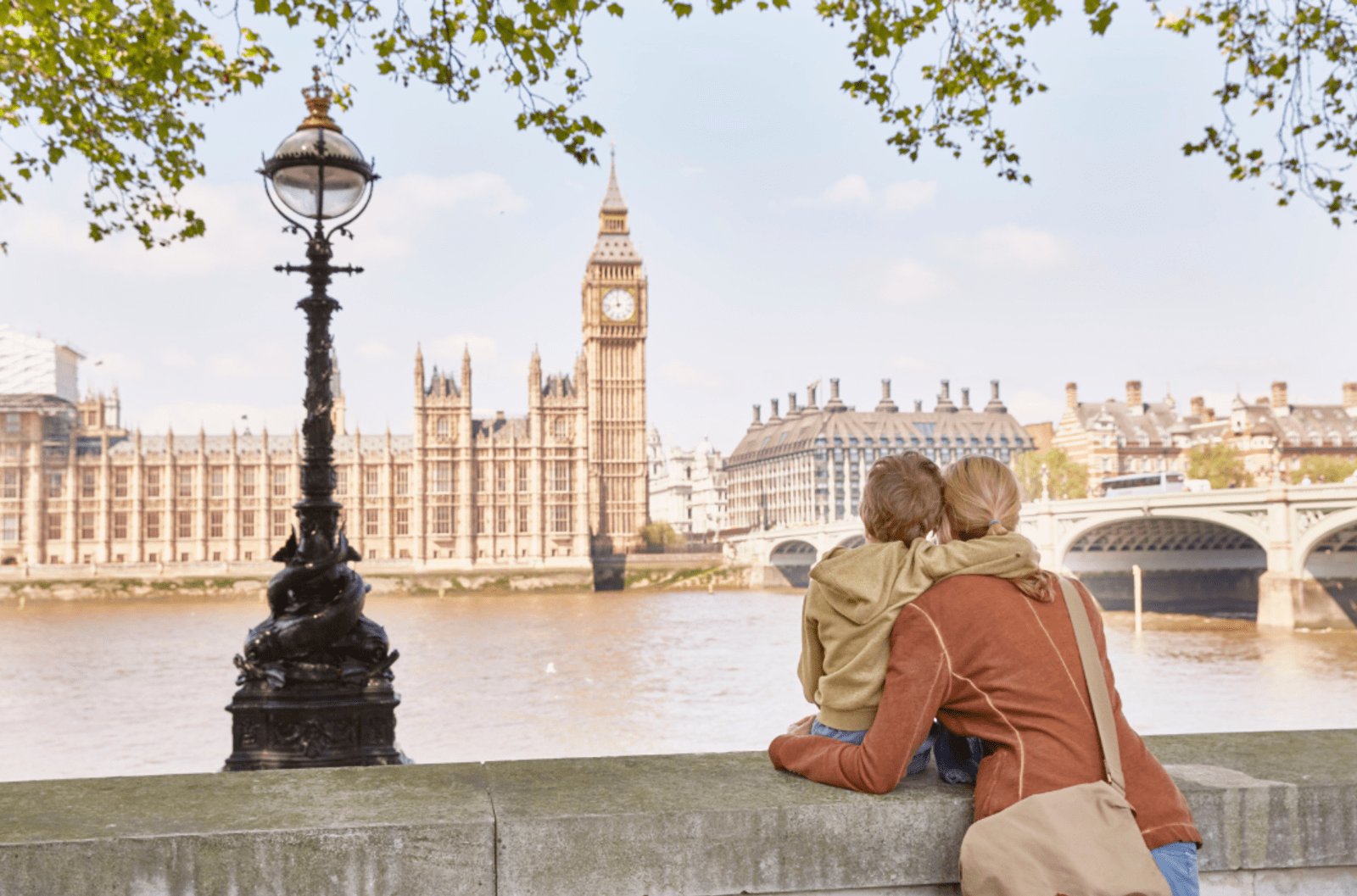 Woman and young boy hugging while looking across the River Thames at Big Ben in London