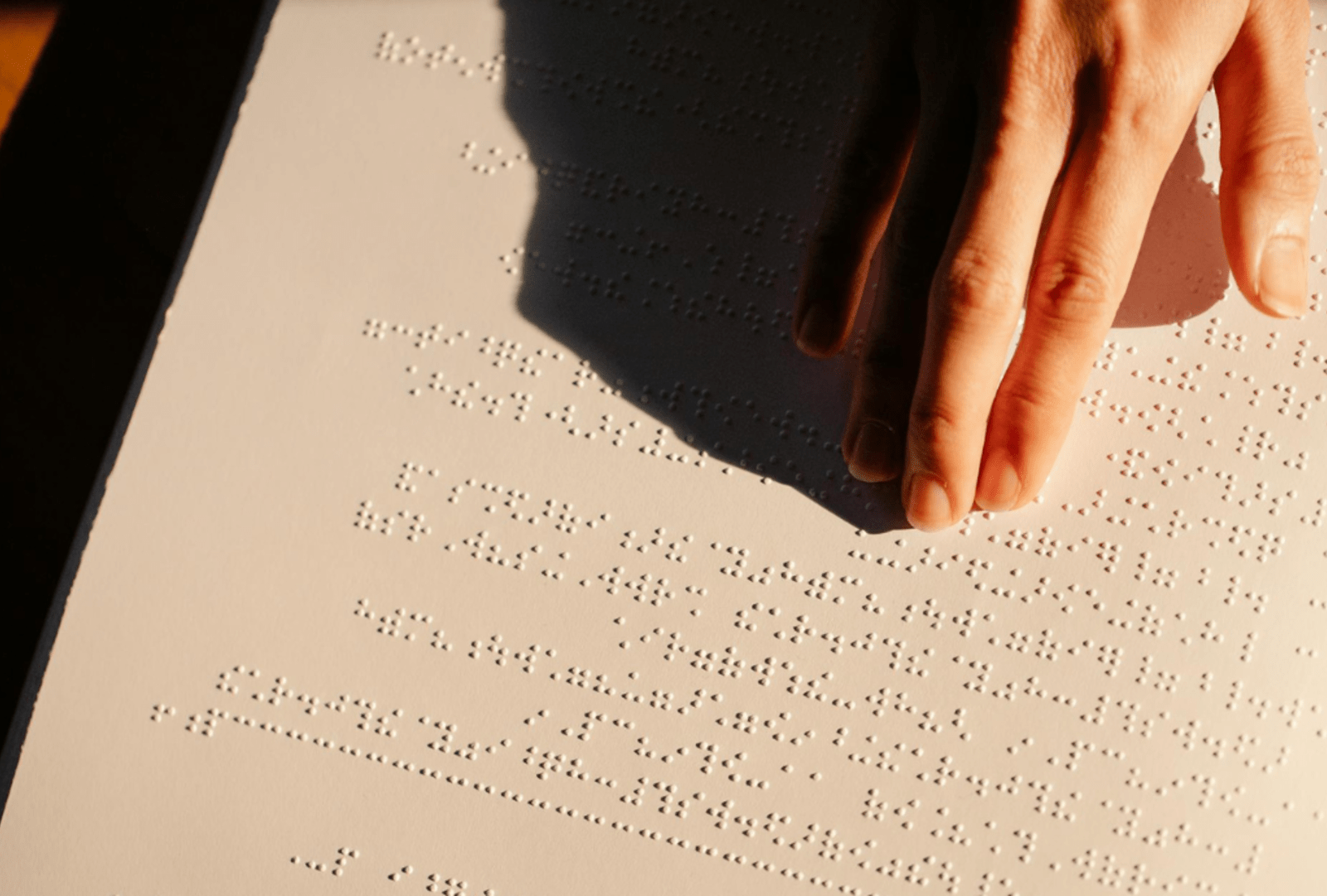 A hand reads a Braille menu