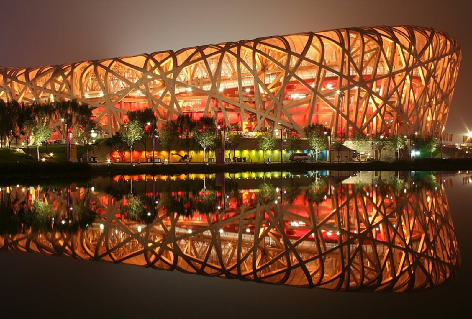 Beijing's 'birds nest" national stadium lit up at night and reflected in a nearby lake 