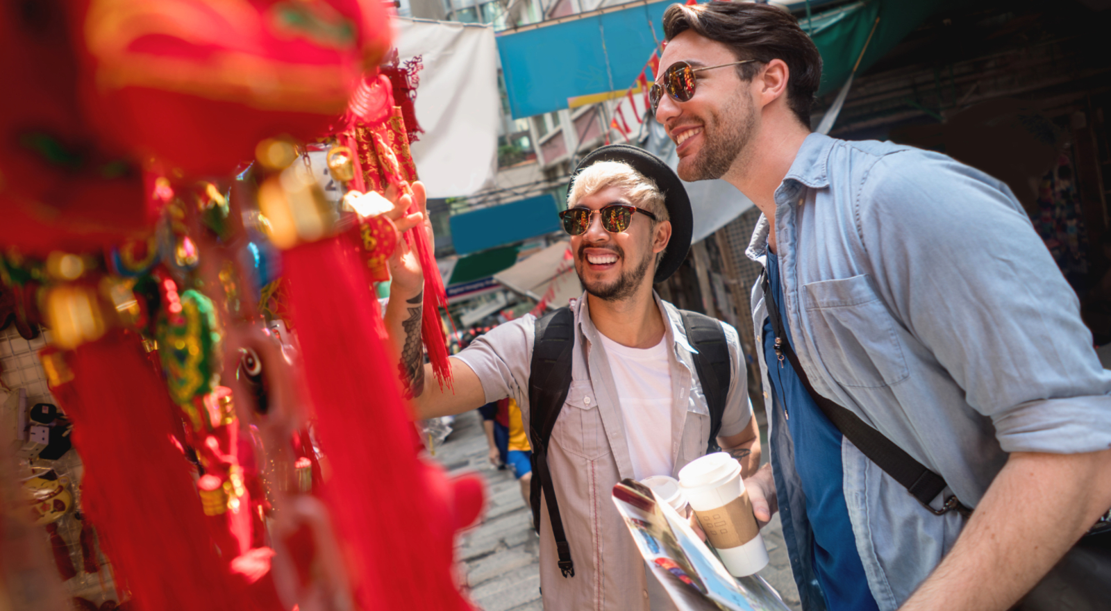 Two young men examine lanterns at a street market