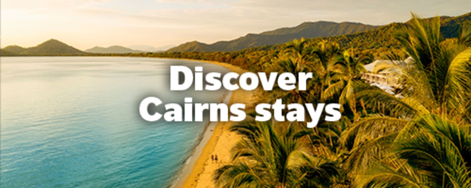 Palm fringed beach and turquoise water beneath tropical hills near Cairns for Discover Cairns stays