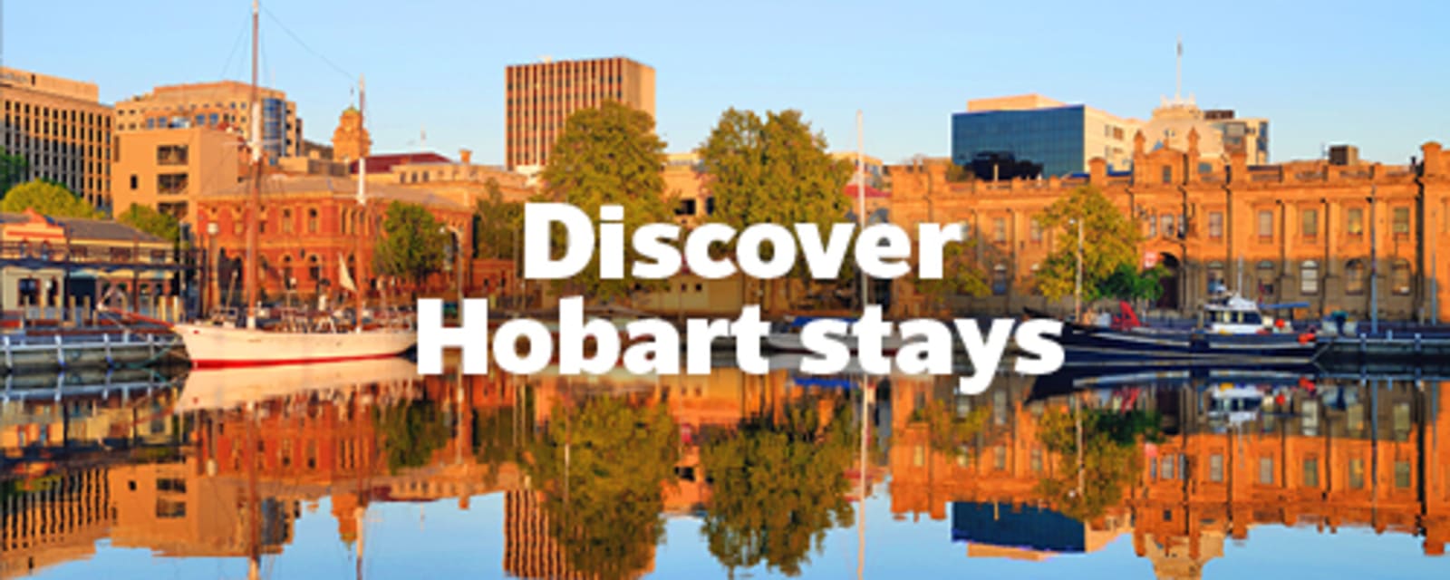Historic waterfront buildings reflected in calm harbour waters for Discover Hobart stays