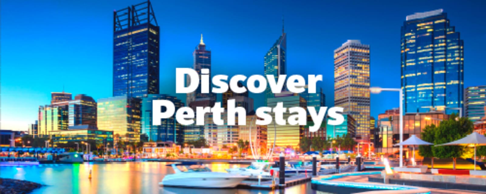 Perth skyline reflected in the river at dusk with boats moored along the marina for Discover Perth stays