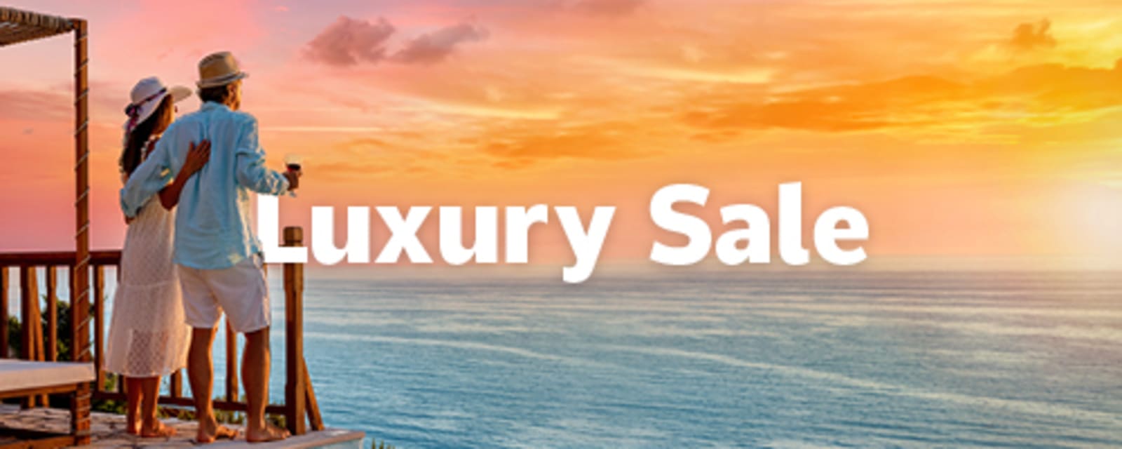 Couple embracing on a balcony overlooking an orange sunset sea for a Luxury Sale