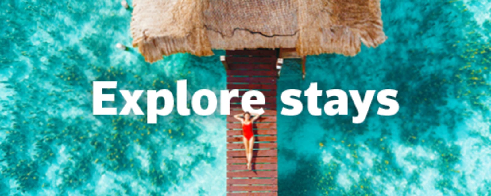Woman relaxing on an overwater bungalow deck above vivid turquoise reef waters for Explore stays