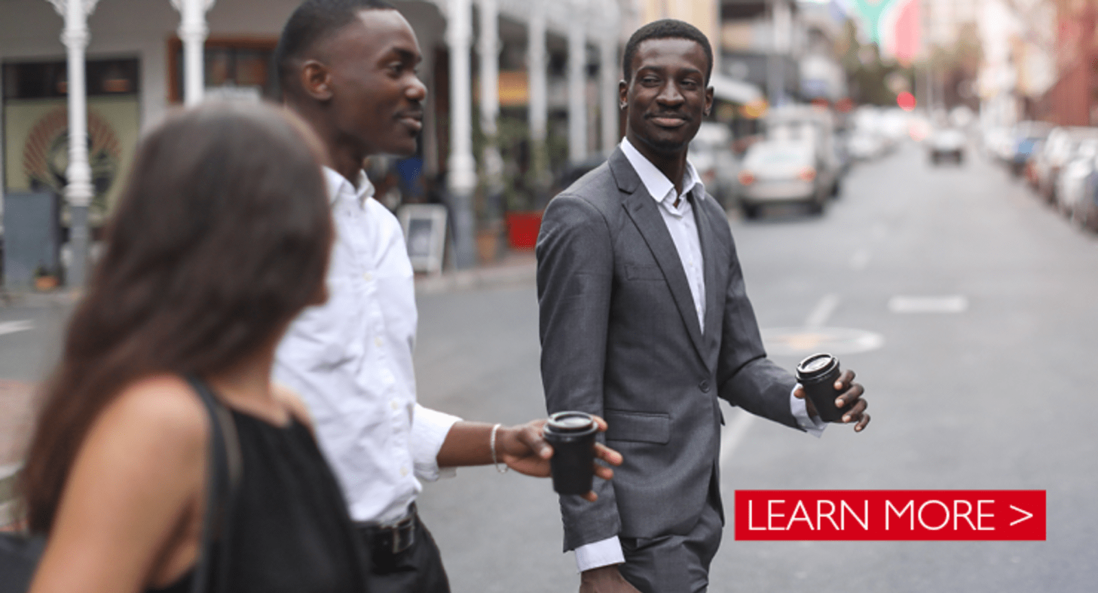 Businessmen crossing a road carrying coffee