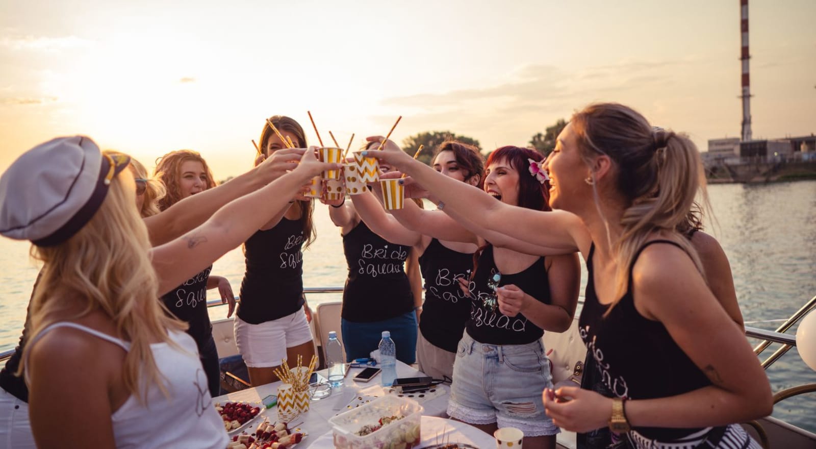 group of women on boat cheersing at sunset