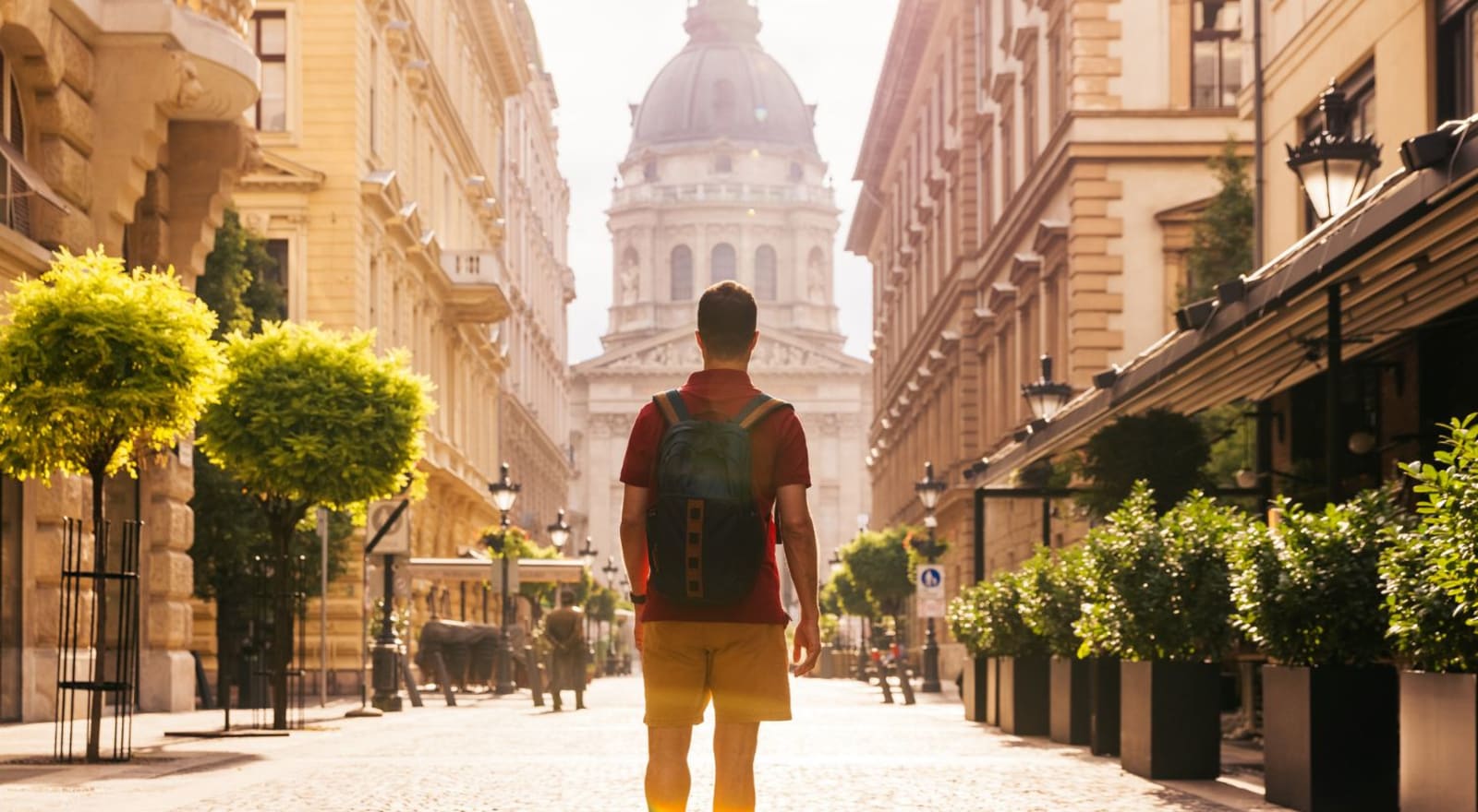 Man standing in middle of street lined with trees and buildings 
